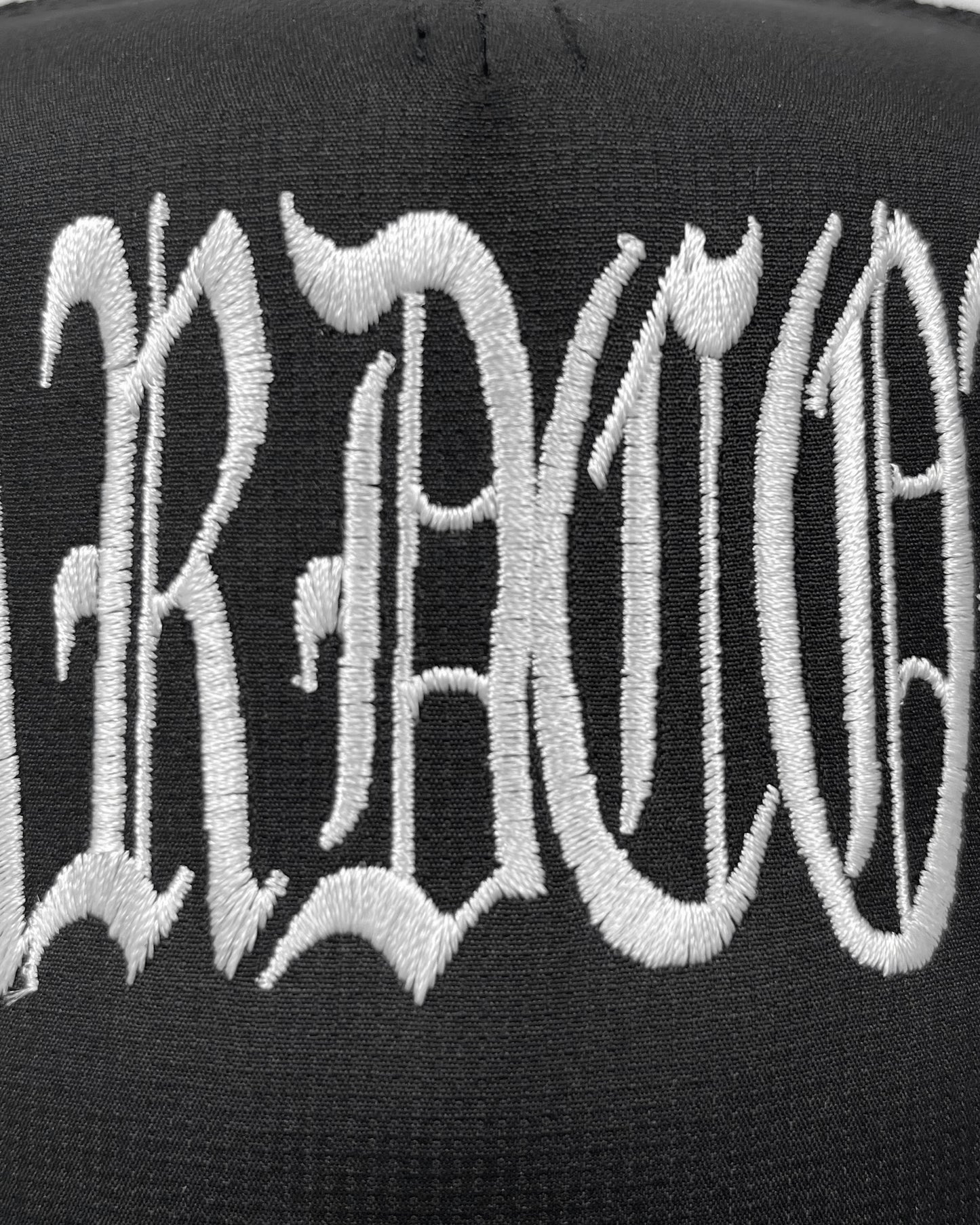 Black cap with white embroidered text on a black background