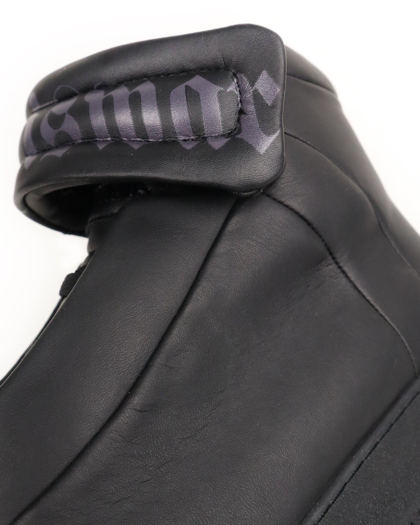 Close-up of a black leather high-top with a brand logo on a white background
