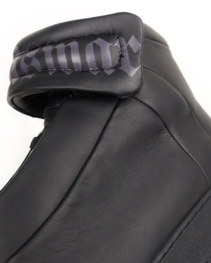 Close-up of a black leather high-top with a brand logo on a white background